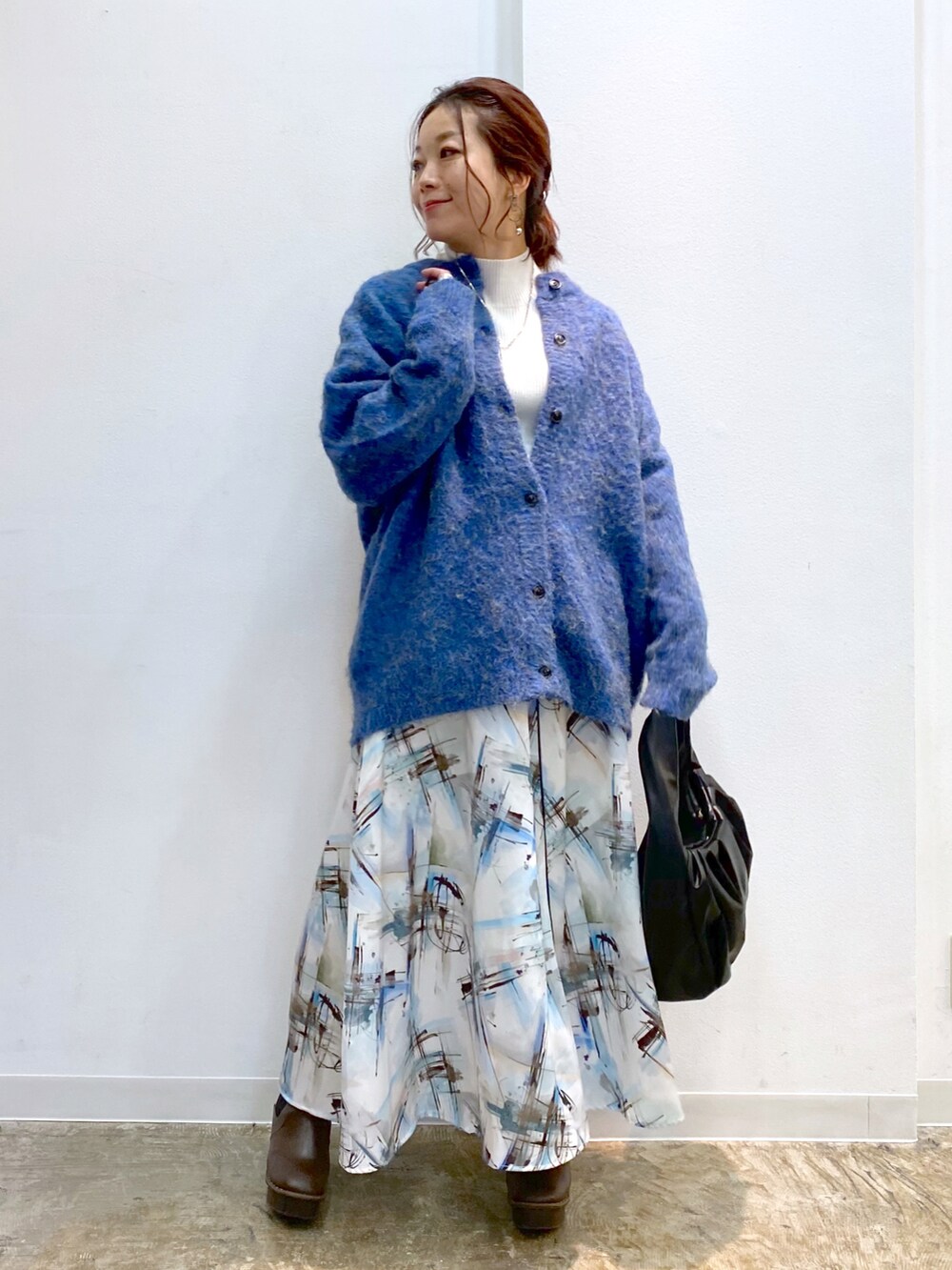 ホワイト系のニット/セーター、ブラック系のハンドバッグ、ブラウン系のブーツを着用したレディースの秋コーディネートの2枚目の写真