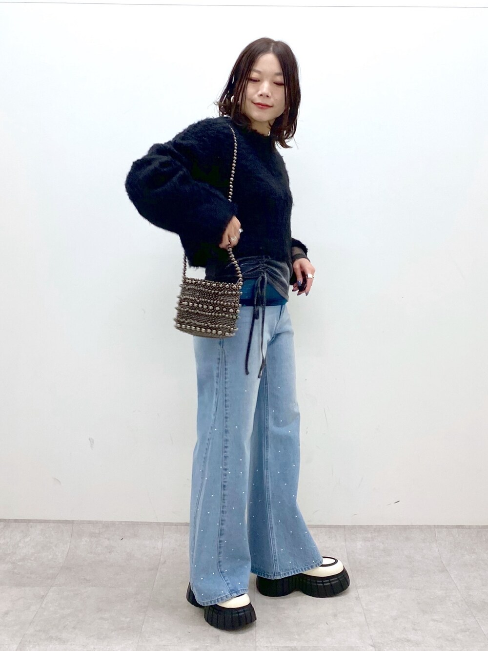 ブラック系のニット/セーター、ブルー系のデニムパンツ、ホワイト系のローファーを着用したレディースの冬コーディネートの3枚目の写真
