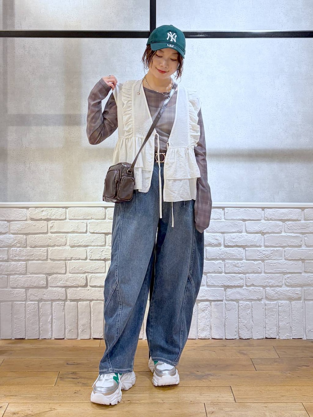 ホワイト系のスニーカー、ブラウン系のショルダーバッグ、ブルー系のデニムパンツを着用したレディースの春コーディネートの8枚目の写真