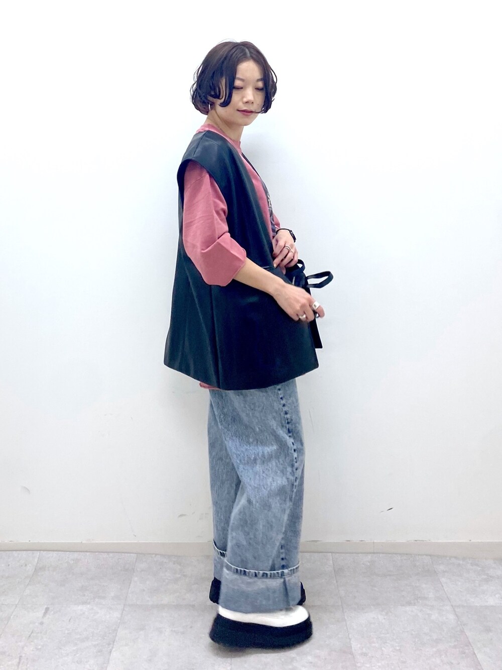 ブルー系のデニムパンツ、ホワイト系のブーツ、ブラック系のショルダーバッグを着用したレディースの秋コーディネートの2枚目の写真