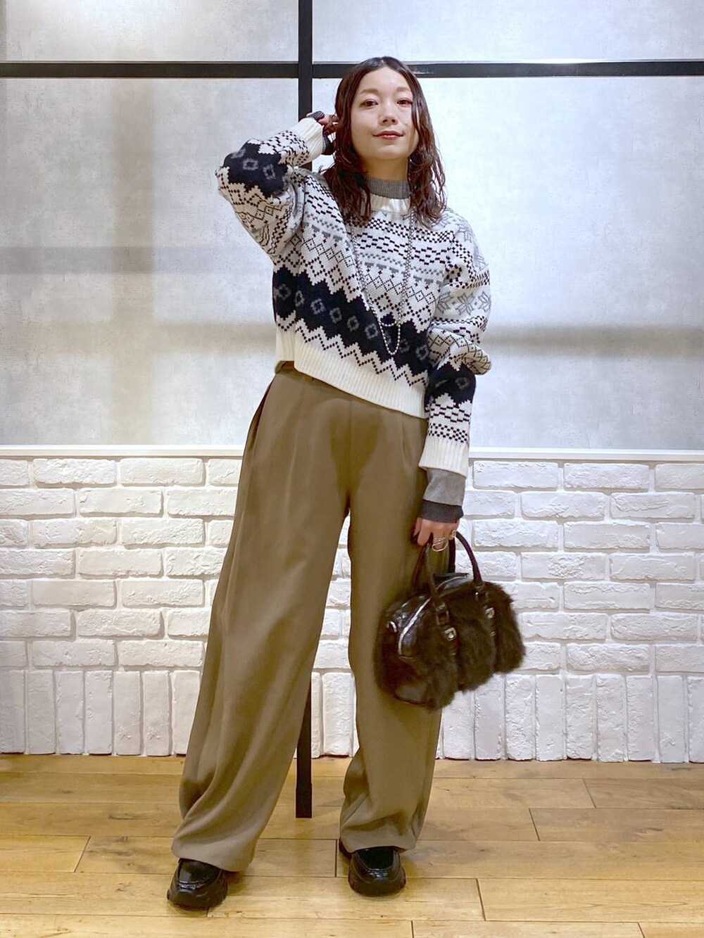 ベージュ系のスラックス、ブラウン系のボストンバッグ、グレー系のニット/セーターを着用したレディースの冬コーディネートの9枚目の写真