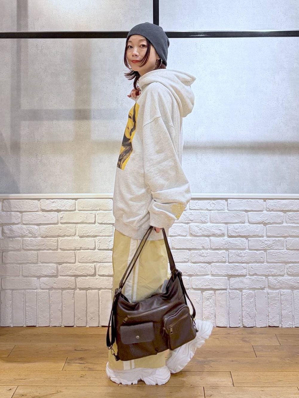 ホワイト系のスニーカー、イエロー系のスウェットパンツ、ブラウン系のショルダーバッグを着用したレディースの春コーディネートの5枚目の写真