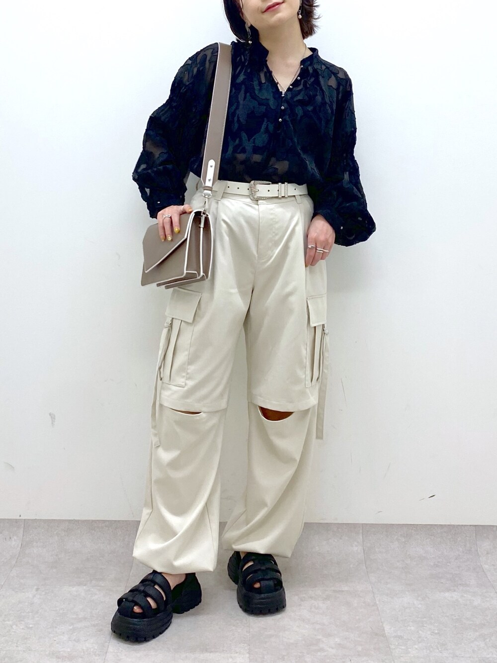 グレー系のパンツ、ブラック系のサンダル、ブラウン系のショルダーバッグを着用したレディースの春コーディネートの4枚目の写真