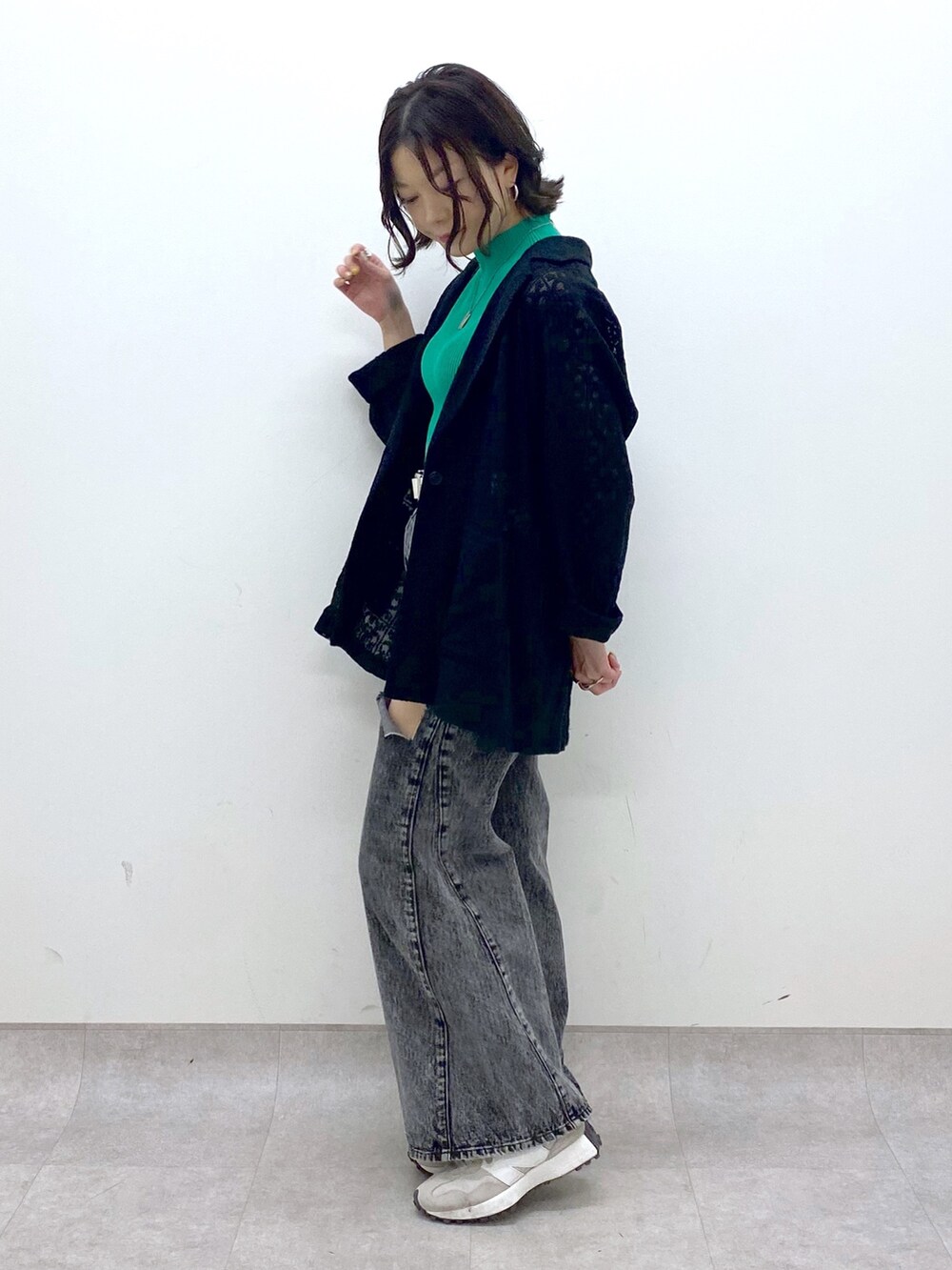 ブラック系のパンツ、ベージュ系のスニーカー、グリーン系のトップスを着用したレディースの春コーディネートの4枚目の写真