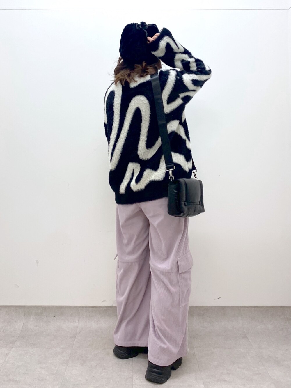 ピンク系のカーゴパンツ、ブラック系のニット/セーター、ブラック系のショルダーバッグを着用したレディースの冬コーディネートの4枚目の写真