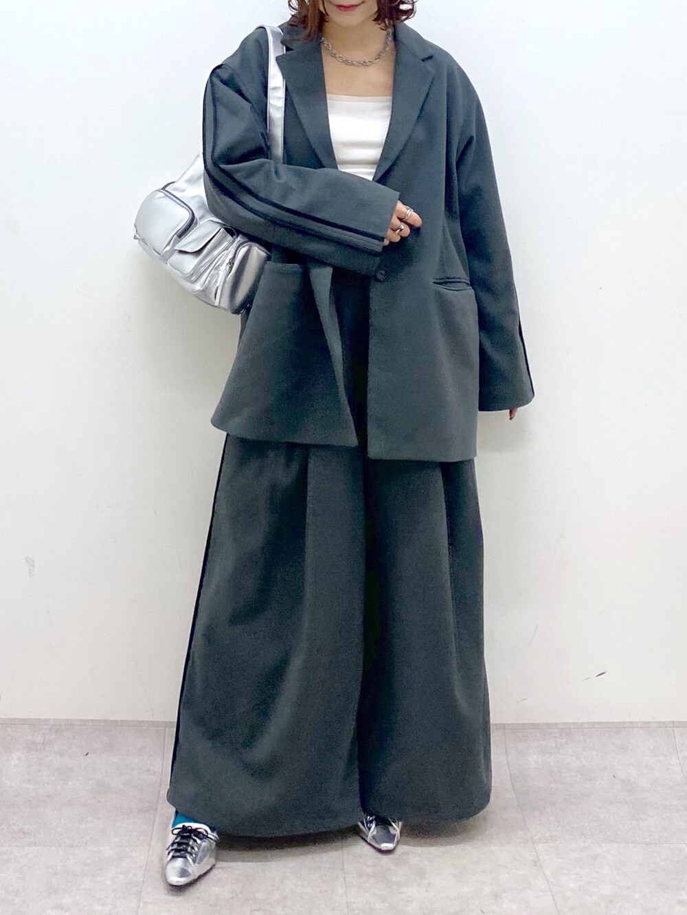 グレー系のスラックス、シルバー系のパンプス、シルバー系のショルダーバッグを着用したレディースの秋コーディネートの3枚目の写真