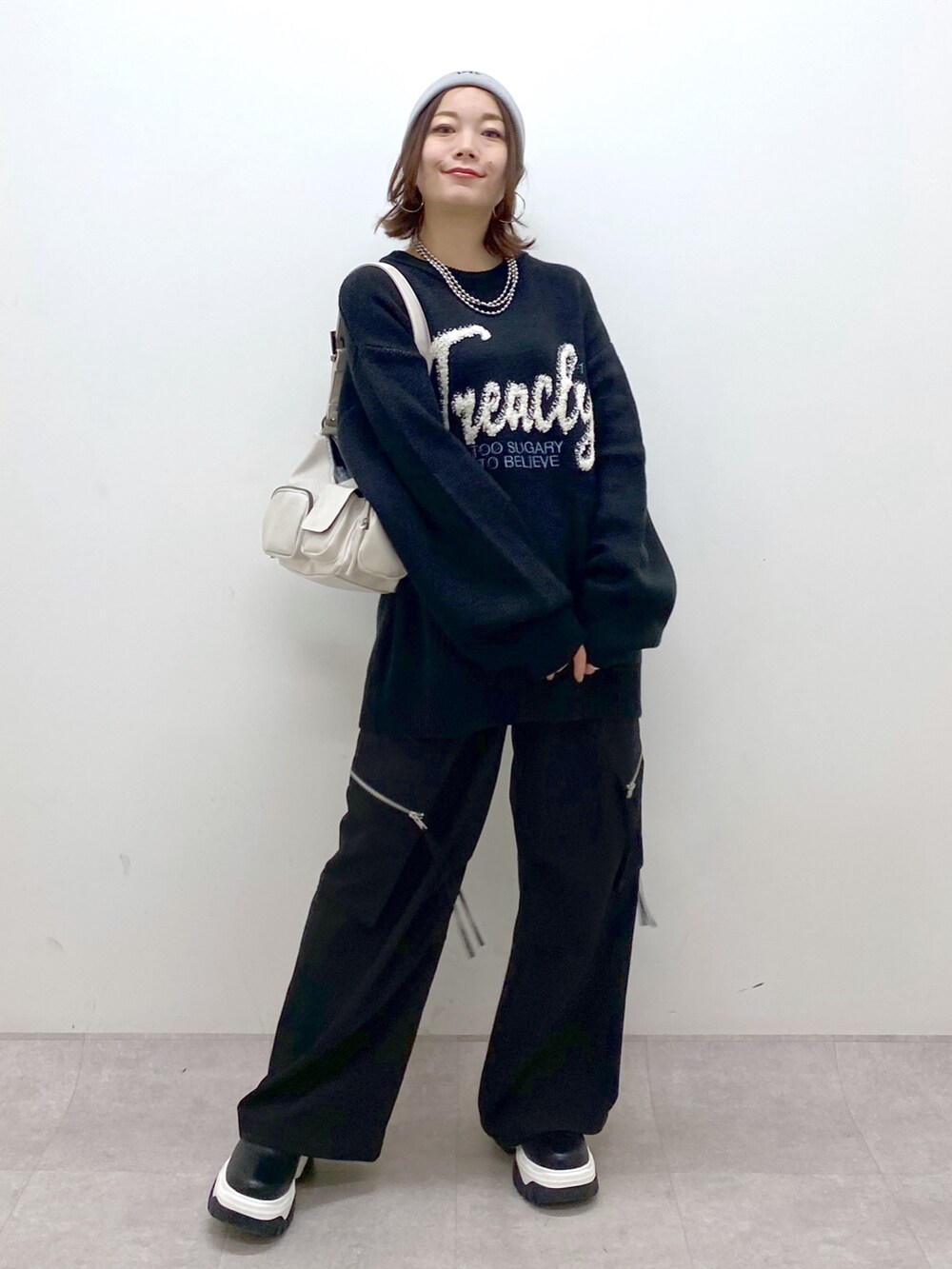 ブラック系のニット/セーター、ブラック系のカーゴパンツ、ホワイト系のショルダーバッグを着用したレディースの冬コーディネートの4枚目の写真
