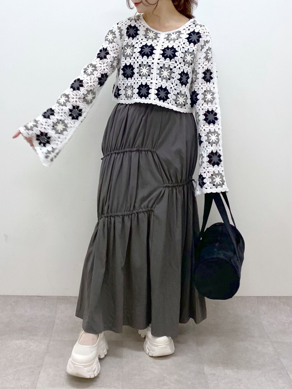 グレー系のスカート、ホワイト系のカーディガン/ボレロ、ブラック系のドラムバッグを着用したレディースの春コーディネートの3枚目の写真