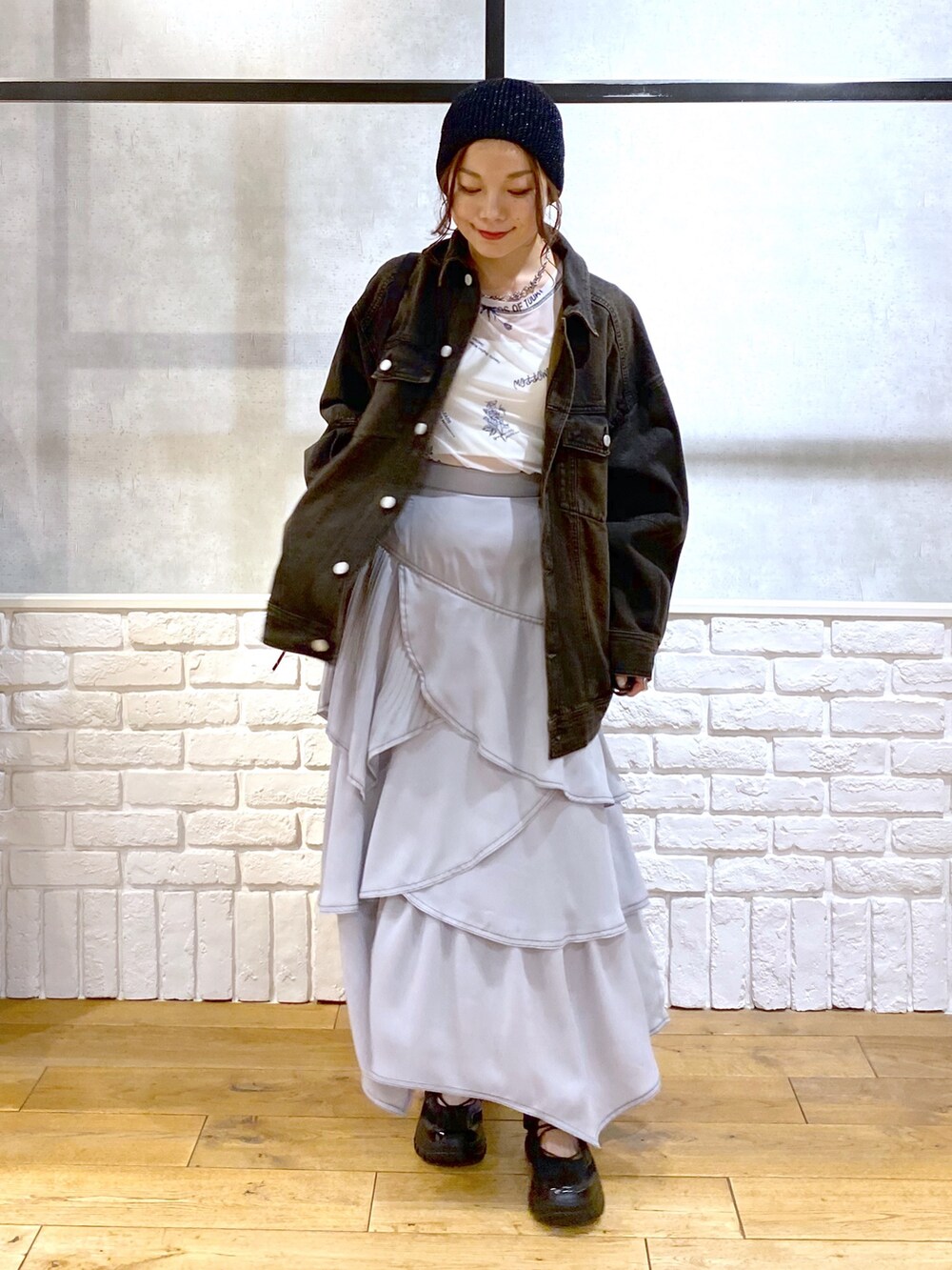 ブラック系のデニムジャケット、グレー系のスカート、ブラック系のスニーカーを着用したレディースの春コーディネートの9枚目の写真