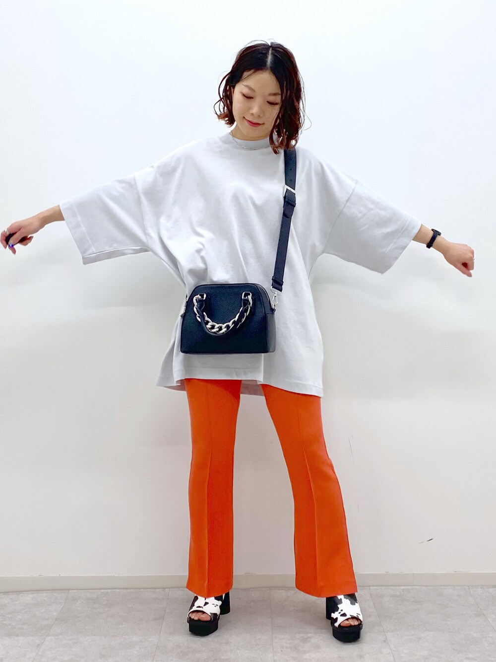 オレンジ系のその他パンツ、ホワイト系のサンダル、ブラック系のショルダーバッグを着用したレディースの春コーディネートの2枚目の写真