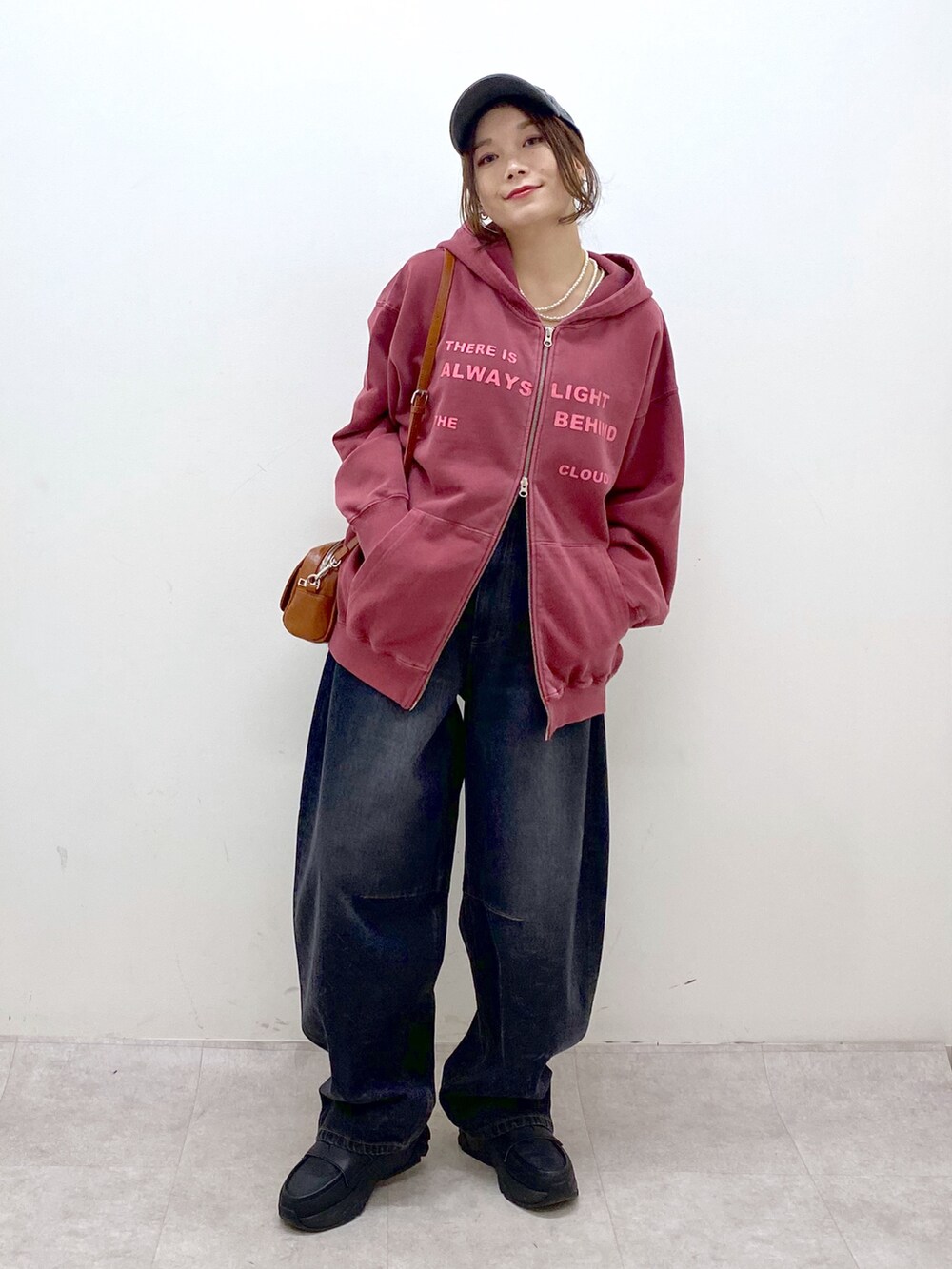 レッド系のスウェット、ブラック系のデニムパンツ、ブラック系のローファーを着用したレディースの冬コーディネートの9枚目の写真