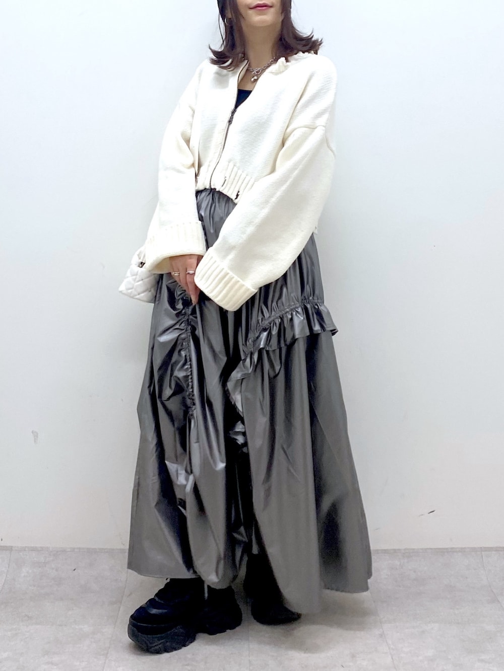 ホワイト系のニット/セーター、シルバー系のスカート、ホワイト系のショルダーバッグを着用したレディースの冬コーディネートの7枚目の写真