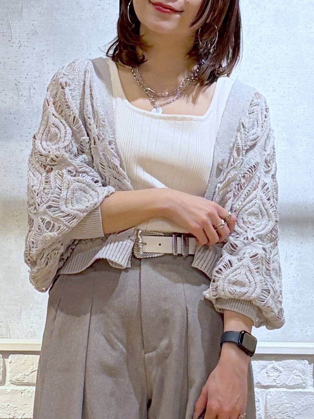 ベージュ系のカーディガン/ボレロ、ホワイト系のタンクトップ、シルバー系のスニーカーを着用したレディースの春コーディネートの2枚目の写真