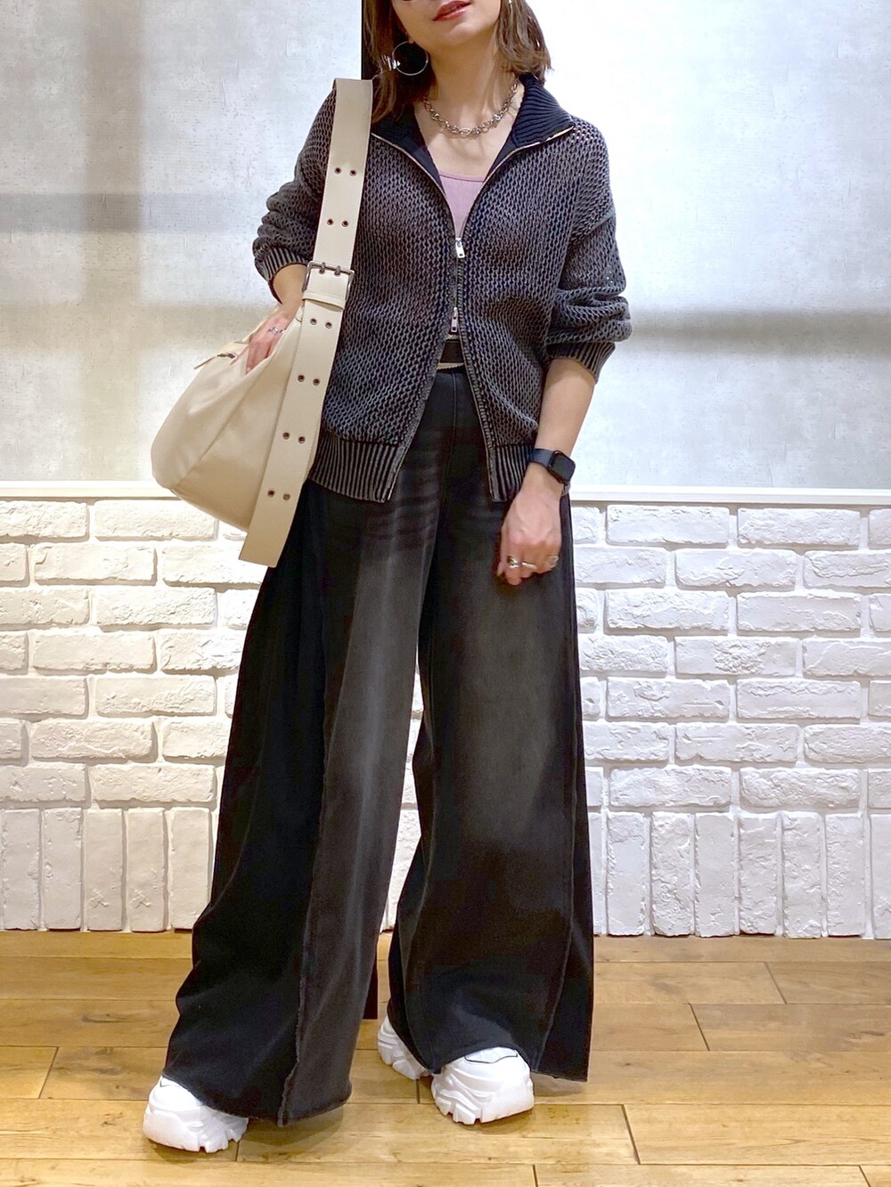 ピンク系のキャミソール、ブラック系のニット/セーター、ブラック系のデニムパンツを着用したレディースの春コーディネートの3枚目の写真