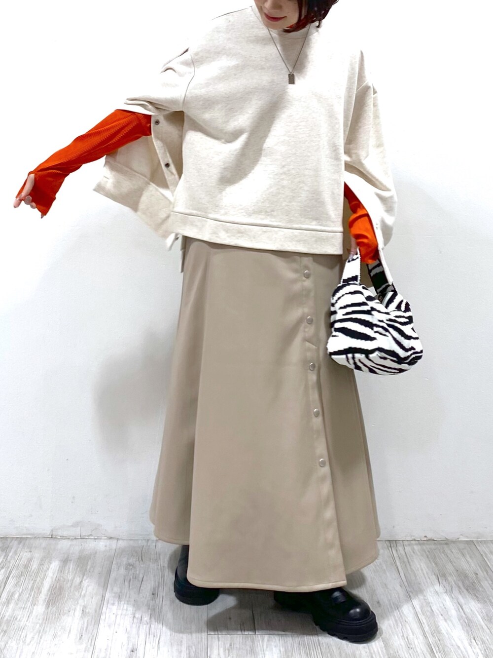 ブラウン系のスカート、ブラック系のバッグ、ベージュ系のトップスを着用したレディースの夏コーディネートの5枚目の写真