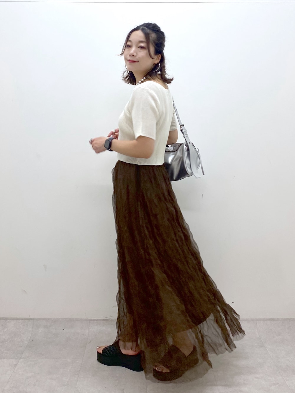 ブラウン系のスカート、ブラック系のサンダル、シルバー系のショルダーバッグを着用したレディースの夏コーディネートの8枚目の写真