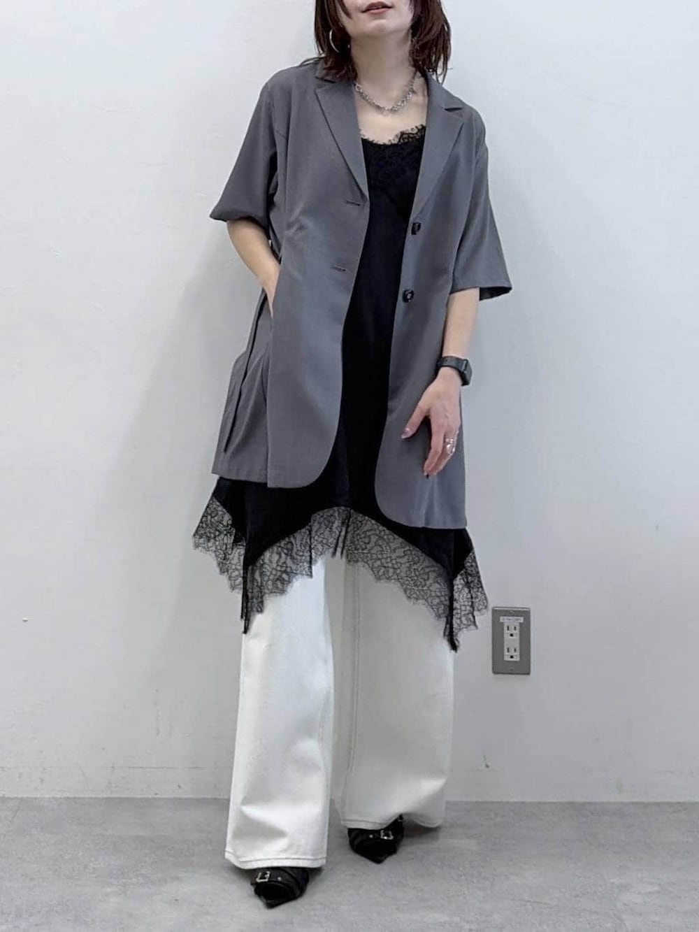 ホワイト系のスラックス、ブラック系のチュニック、ブラック系のサンダルを着用したレディースの春コーディネートの3枚目の写真