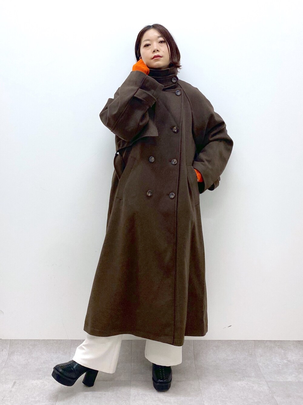 ブラック系のトップス、オレンジ系のトップス、ホワイト系のパンツを着用したレディースの秋コーディネートの5枚目の写真