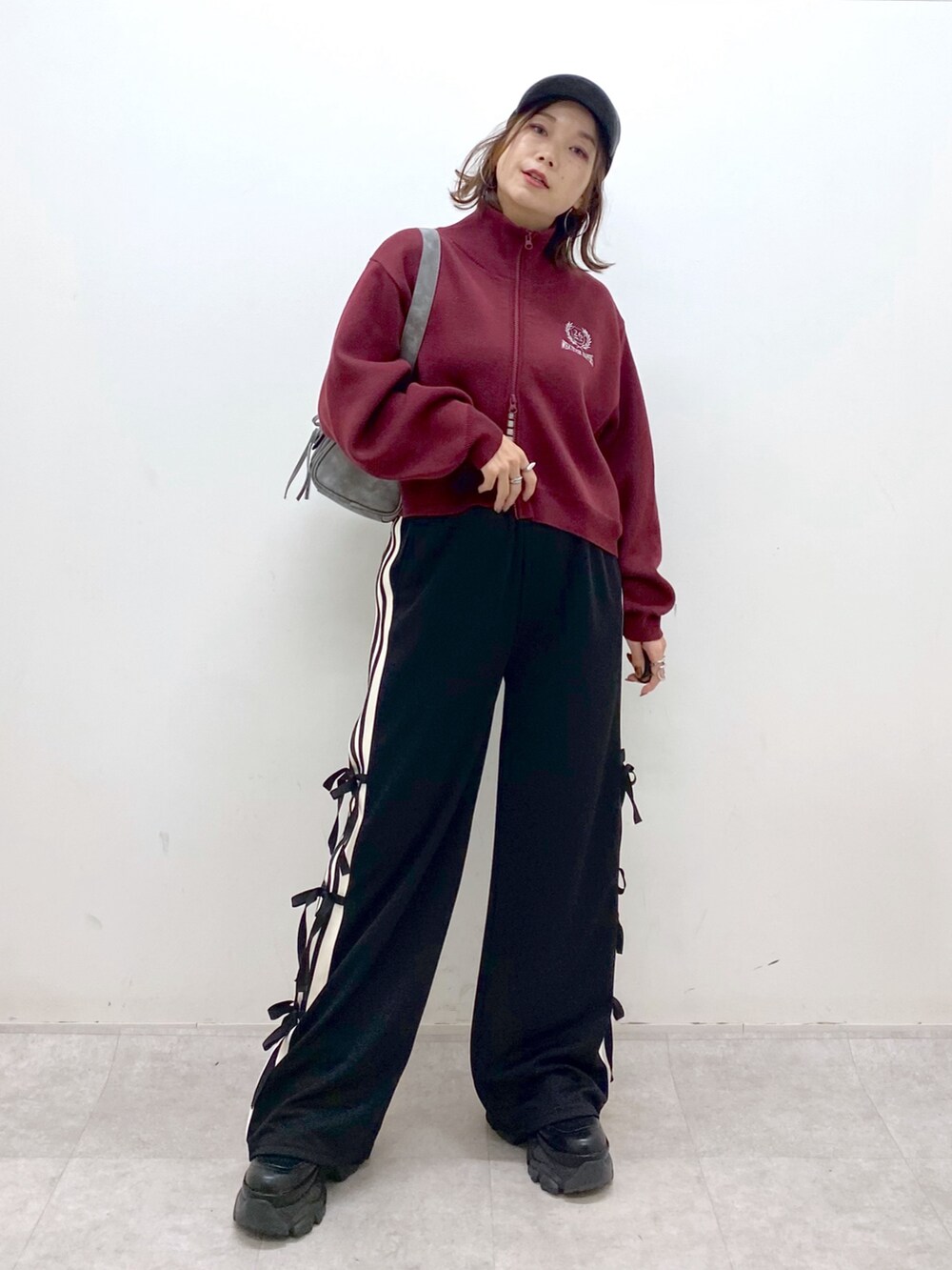 レッド系のニット/セーター、ブラック系のその他パンツ、ブラック系のブーツを着用したレディースの秋コーディネートの9枚目の写真