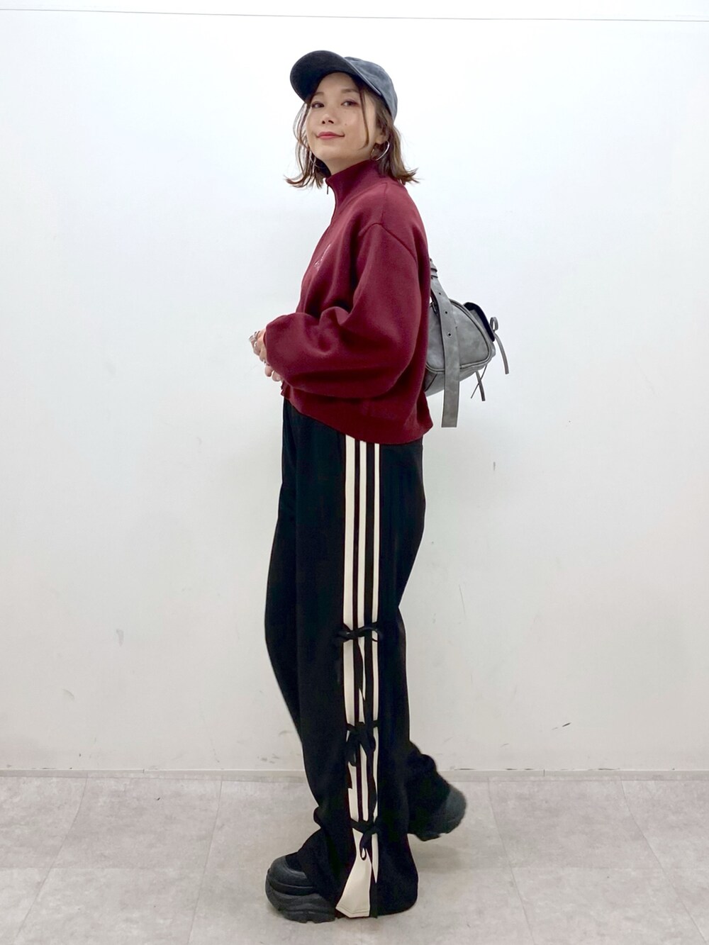 レッド系のニット/セーター、ブラック系のその他パンツ、ブラック系のブーツを着用したレディースの秋コーディネートの6枚目の写真