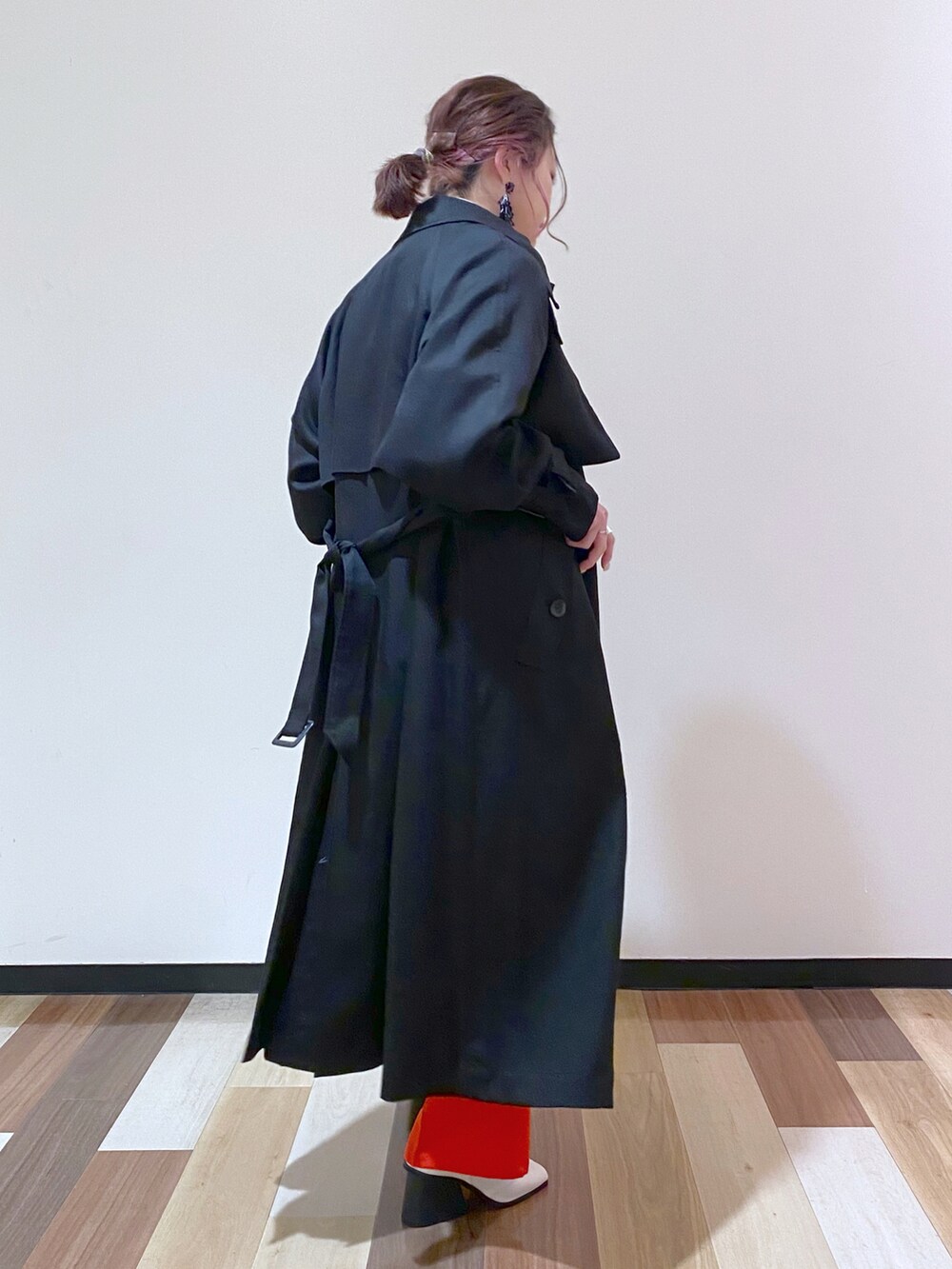 ブラック系のトレンチコート、レッド系のスラックス、ホワイト系のパンプスを着用したレディースの冬コーディネートの3枚目の写真