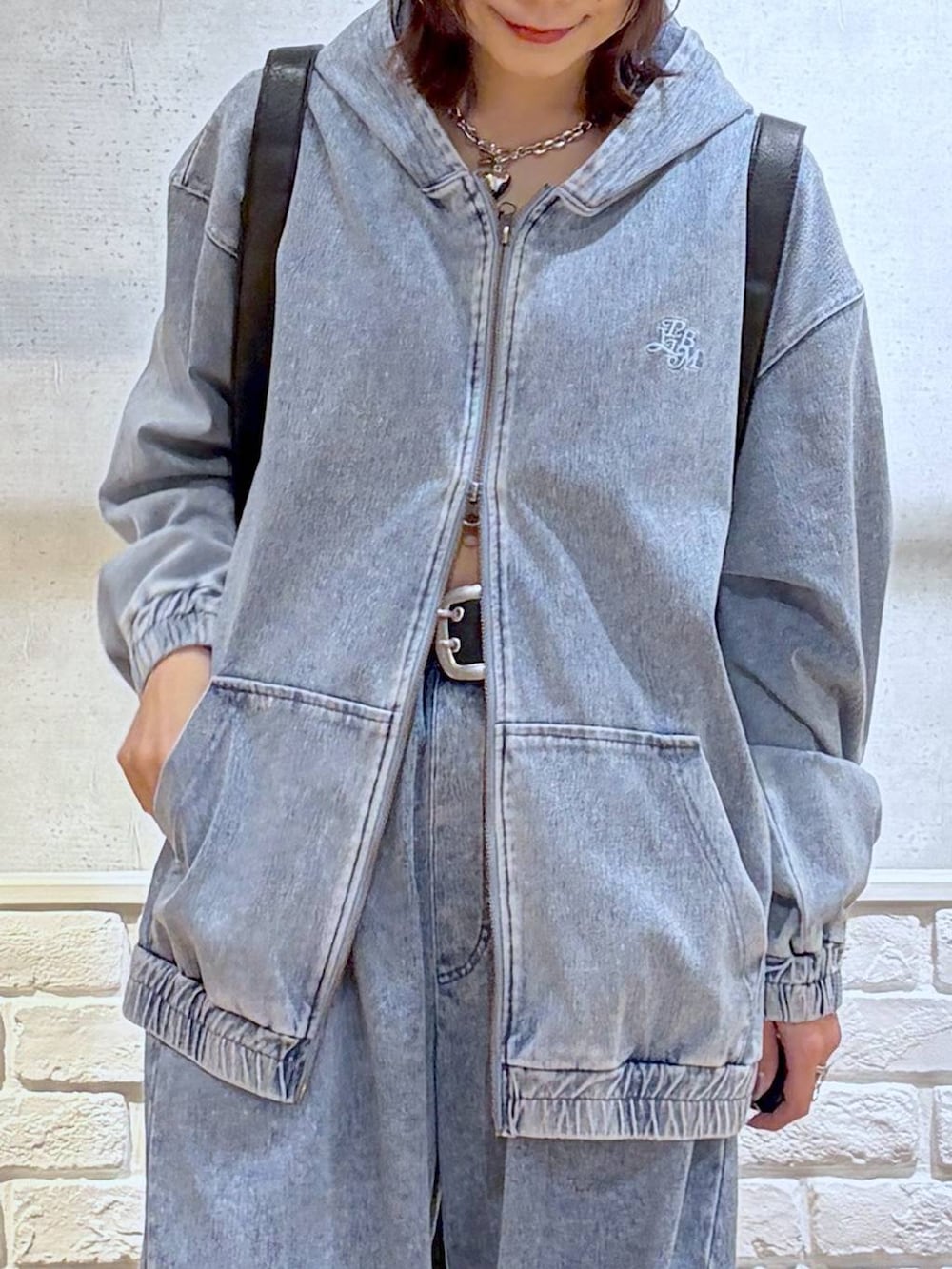 ブラック系のスニーカー、ブラック系のショルダーバッグ、ブルー系のパーカーを着用したレディースの春コーディネートの2枚目の写真