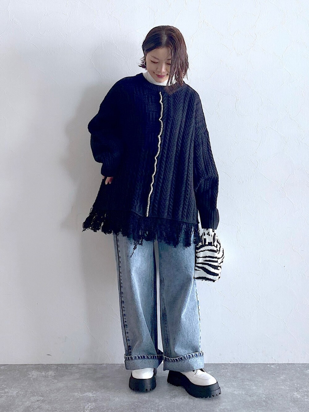 ブラック系のニット/セーター、ブルー系のデニムパンツ、ホワイト系のブーツを着用したレディースの夏コーディネートの2枚目の写真