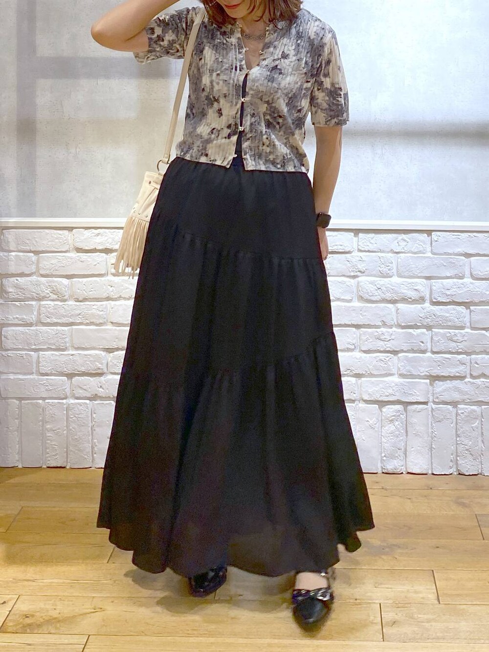 ブラック系のパンプス、ブラック系のスカート、ホワイト系のショルダーバッグを着用したレディースの夏コーディネートの3枚目の写真