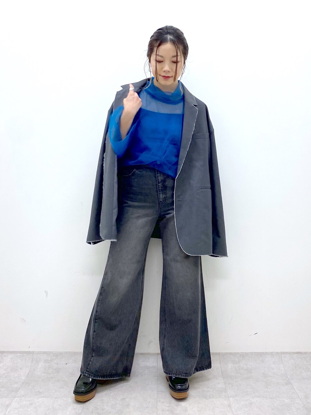 グレー系のテーラードジャケット、ブルー系のシャツ/ブラウス、ブラック系のデニムパンツを着用したレディースの秋コーディネートの3枚目の写真