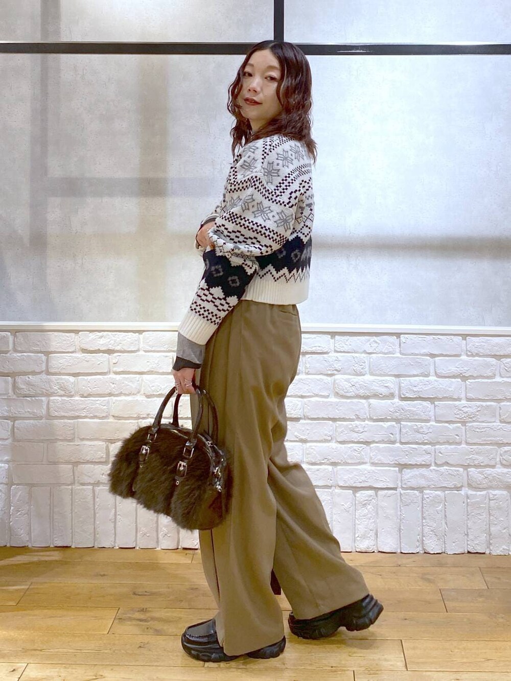 ベージュ系のスラックス、ブラウン系のボストンバッグ、グレー系のニット/セーターを着用したレディースの冬コーディネートの6枚目の写真