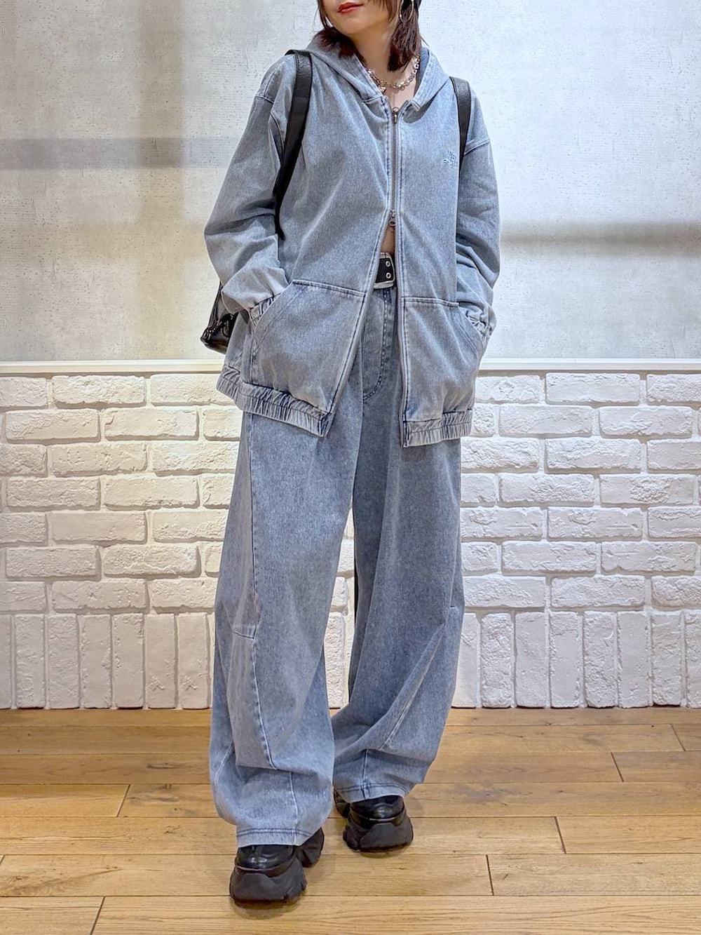 ブラック系のスニーカー、ブラック系のショルダーバッグ、ブルー系のパーカーを着用したレディースの春コーディネートの3枚目の写真