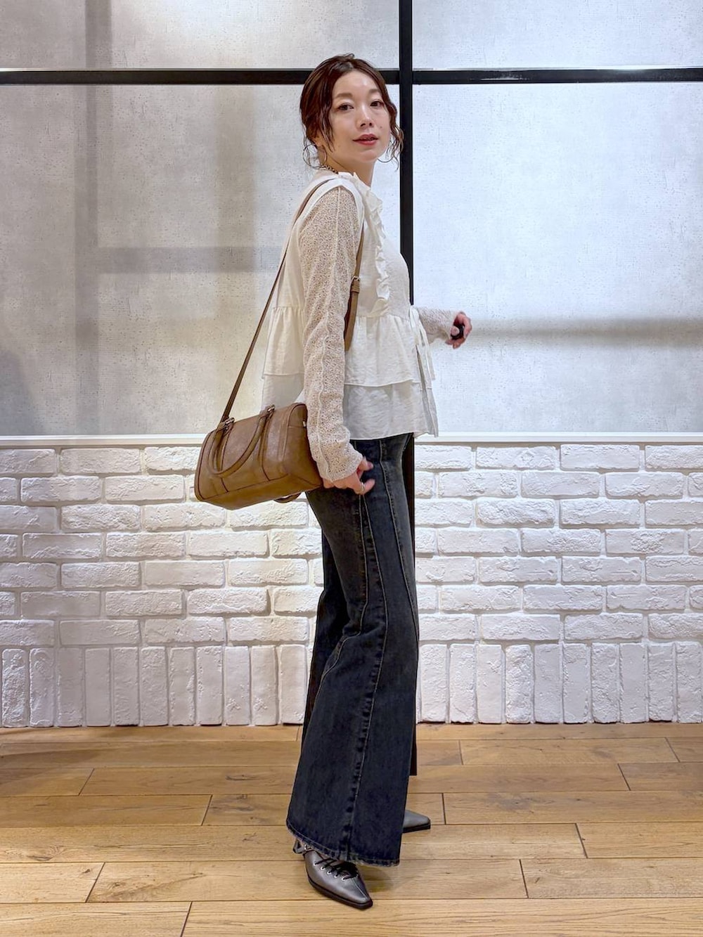 ブルー系のデニムパンツ、ブラウン系のボストンバッグ、ブラウン系のサンダルを着用したレディースの春コーディネートの5枚目の写真