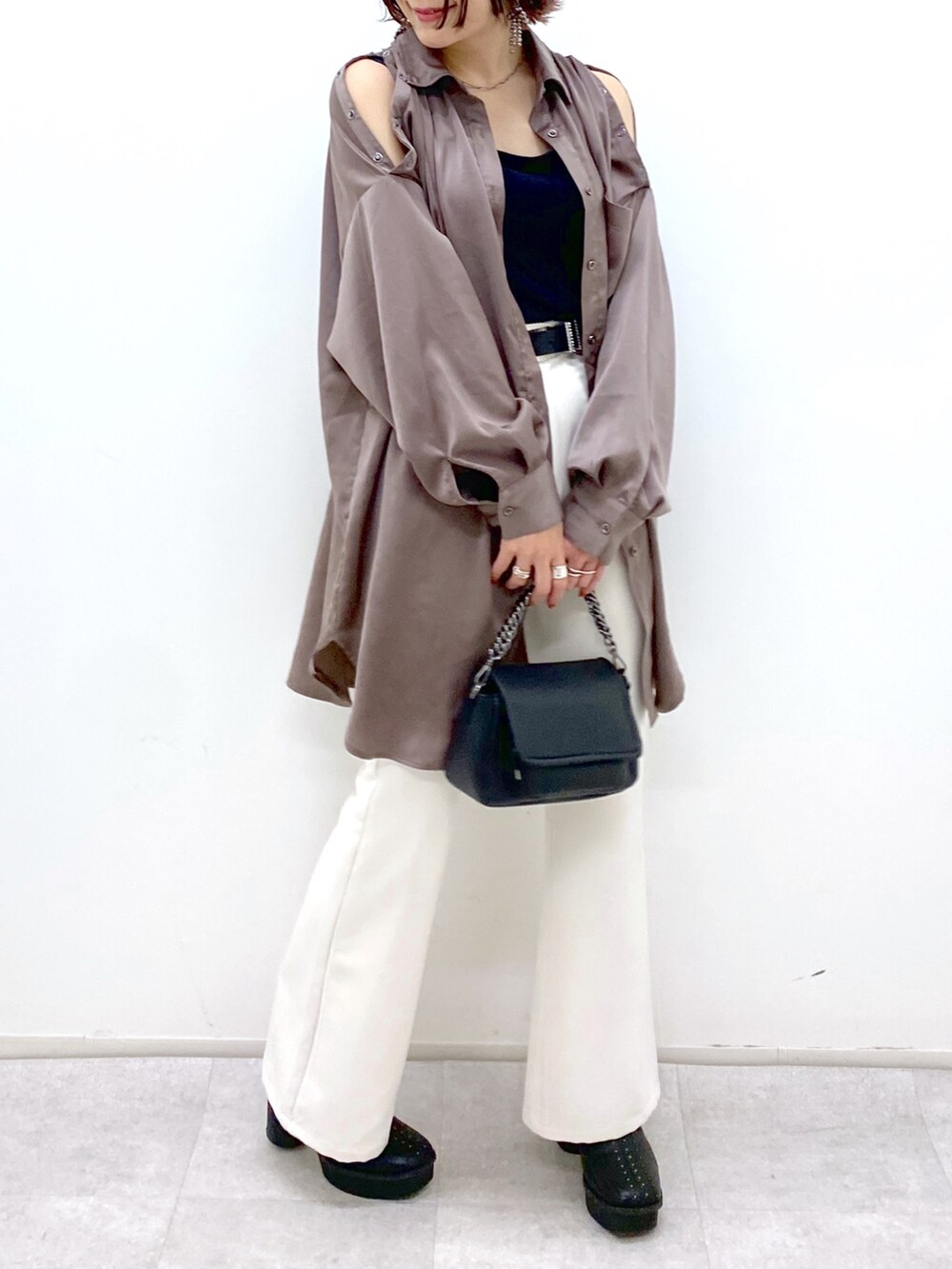 ホワイト系のパンツ、ブラック系のブーツ、ブラック系のバッグを着用したレディースの秋コーディネートの4枚目の写真