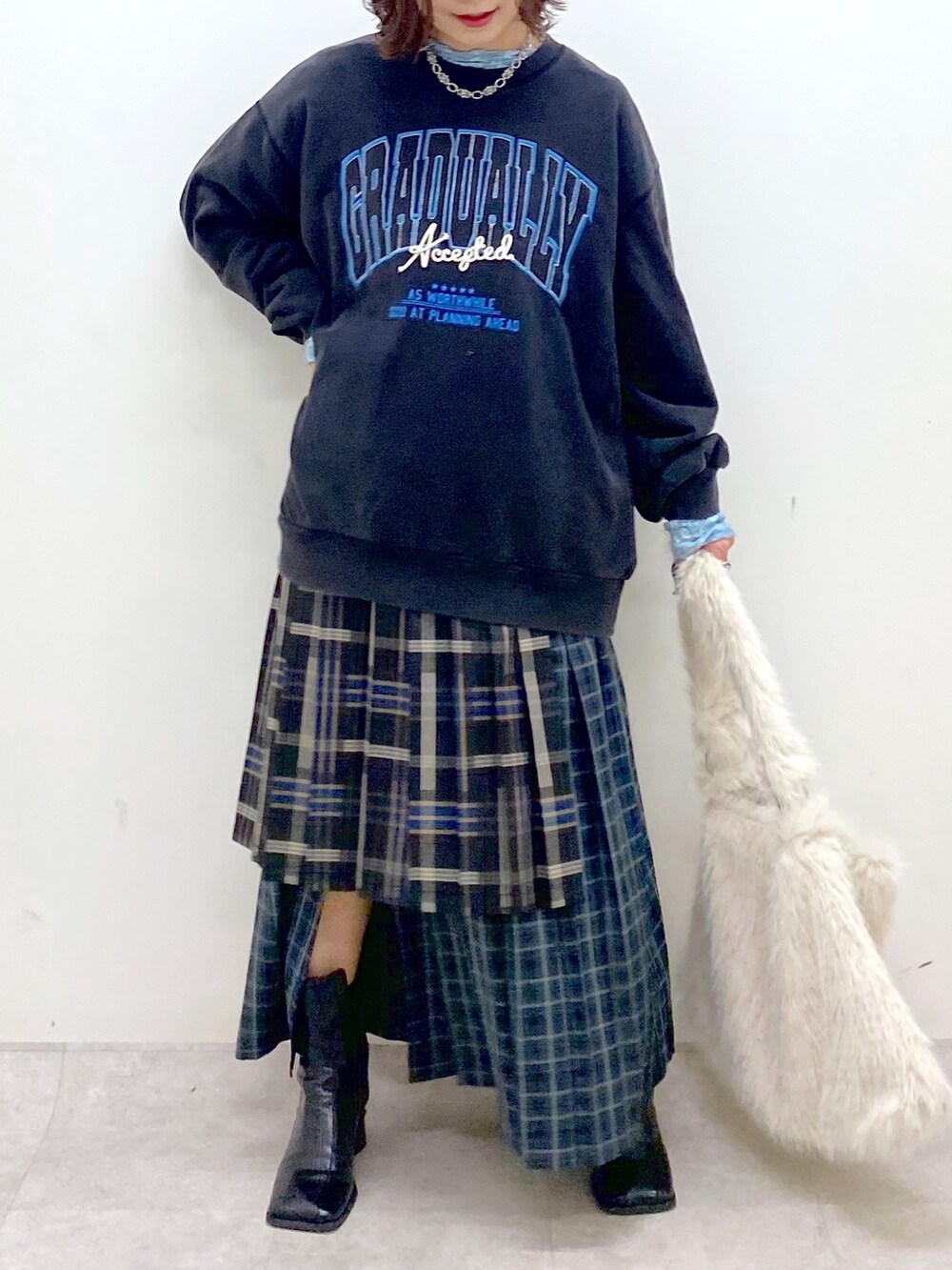 グレー系のスウェット、ブルー系のスカート、ホワイト系のショルダーバッグを着用したレディースの秋コーディネートの3枚目の写真