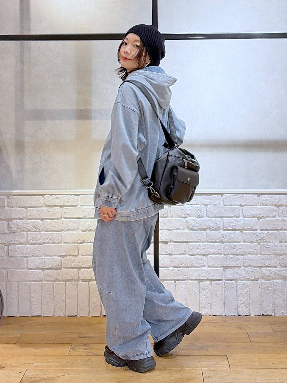 ブラック系のスニーカー、ブラック系のショルダーバッグ、ブルー系のパーカーを着用したレディースの春コーディネートの5枚目の写真