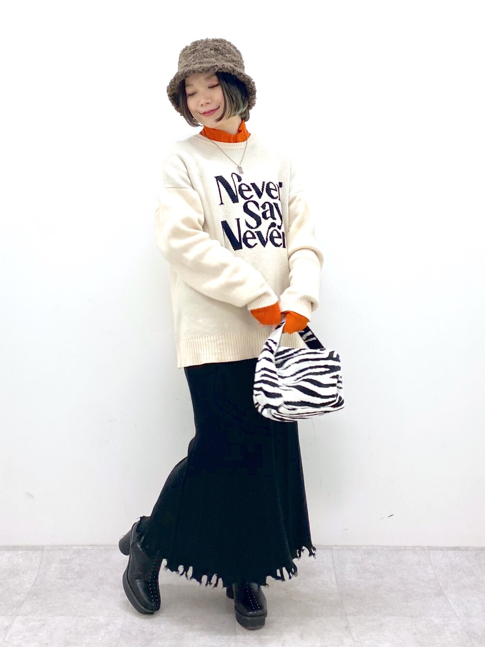 ホワイト系のトップス、オレンジ系のトップス、ブラック系のスカートを着用したレディースの冬コーディネートの5枚目の写真