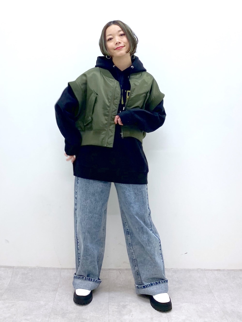 グリーン系のモッズコート、ブラック系のトップス、ブルー系のデニムパンツを着用したレディースの冬コーディネートの3枚目の写真