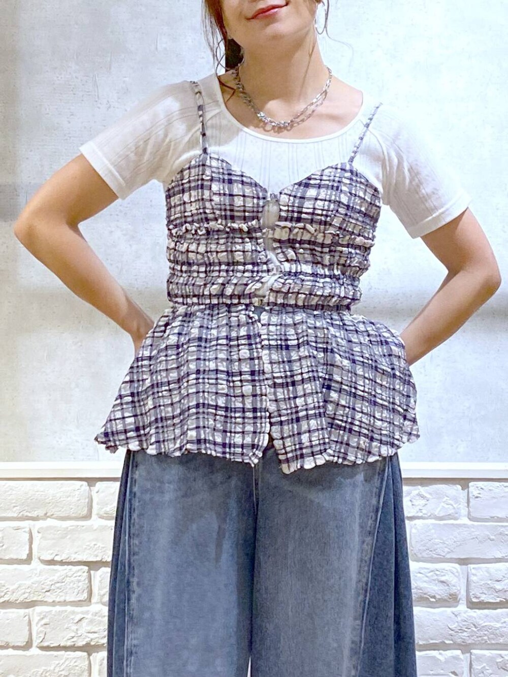 ホワイト系のサンダル、ブルー系のデニムパンツ、ブルー系のキャミソールを着用したレディースの夏コーディネートの2枚目の写真
