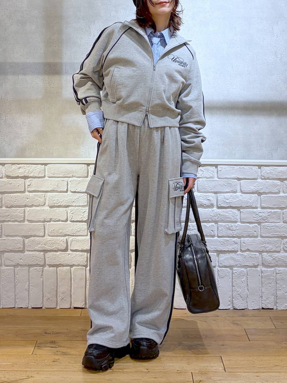 ブラック系のブーツ、ブラック系のボストンバッグ、グレー系のジャージを着用したレディースの冬コーディネートの2枚目の写真