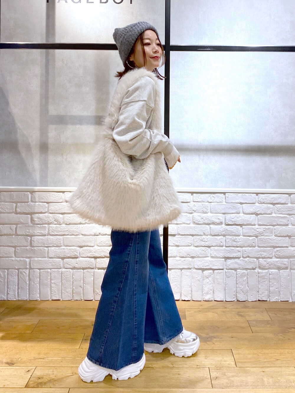 ホワイト系のショルダーバッグ、ブルー系のデニムパンツ、ホワイト系のブーツを着用したレディースの秋コーディネートの5枚目の写真