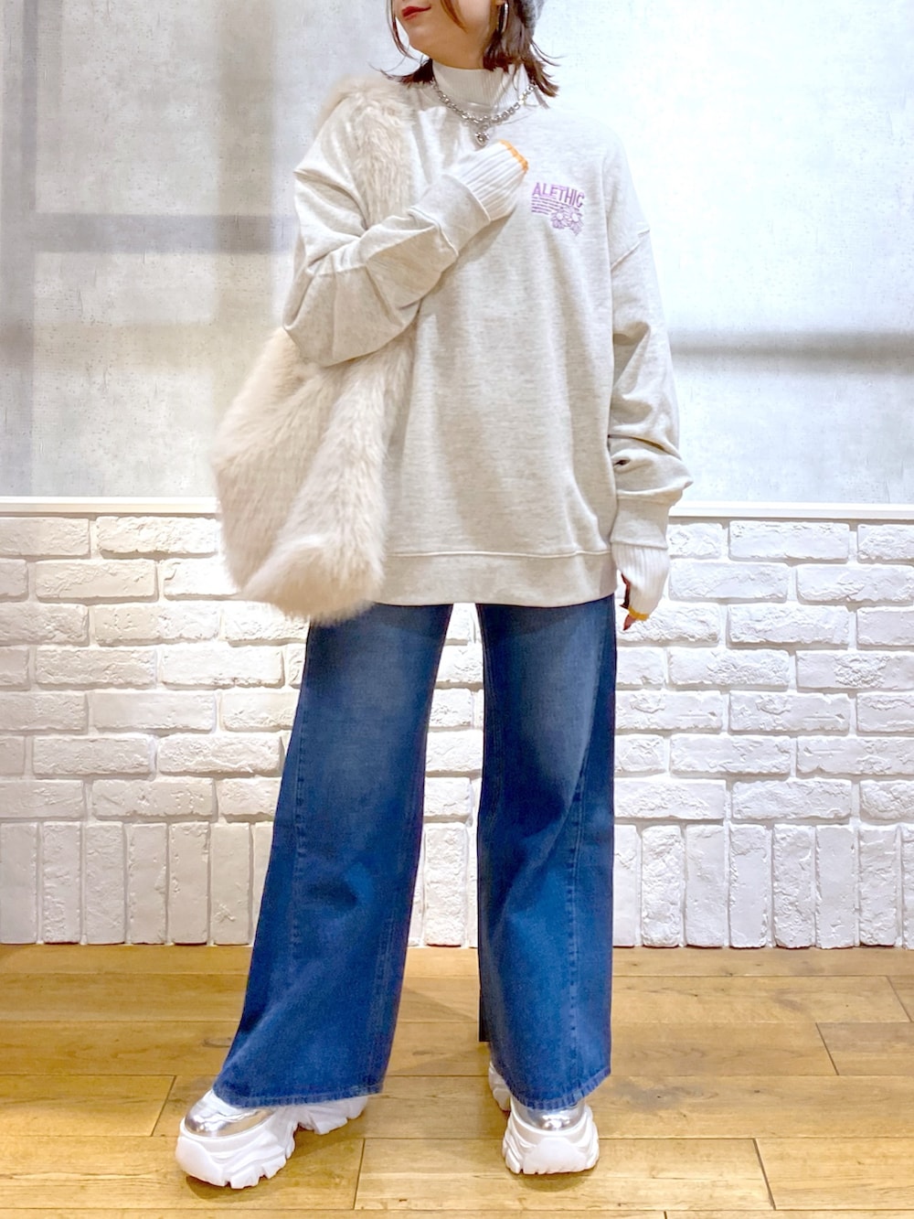 ホワイト系のショルダーバッグ、ブルー系のデニムパンツ、ホワイト系のブーツを着用したレディースの秋コーディネートの3枚目の写真