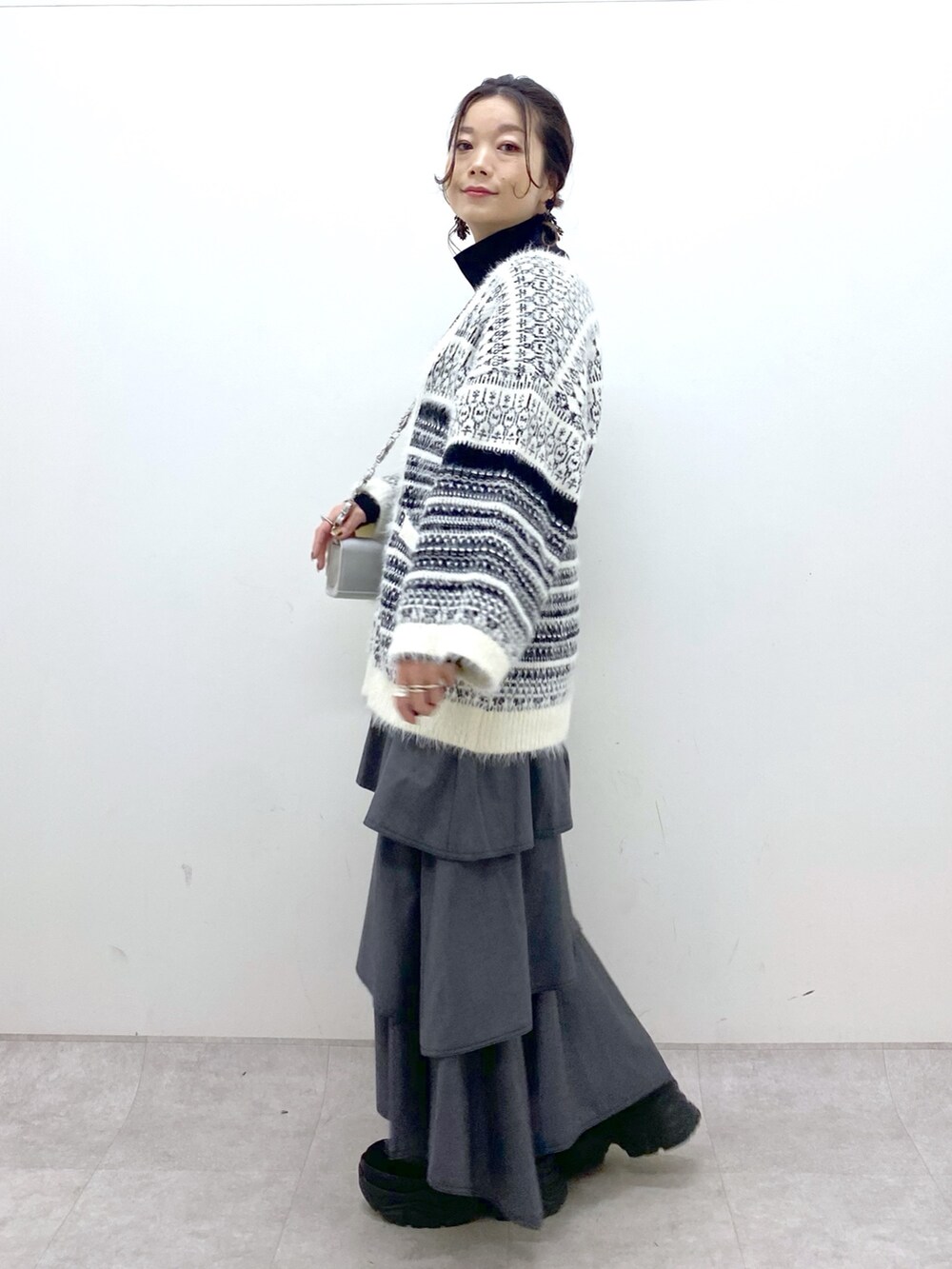 ホワイト系のカーディガン/ボレロ、グレー系のスカート、ブラック系のスニーカーを着用したレディースの冬コーディネートの6枚目の写真