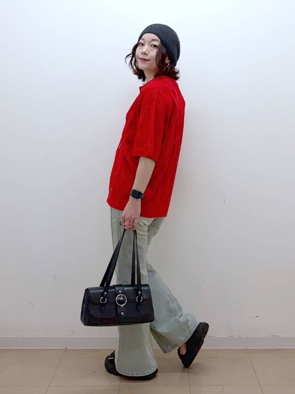 レッド系のポロシャツ、ブルー系のデニムパンツ、ブラック系のサンダルを着用したレディースの夏コーディネートの5枚目の写真