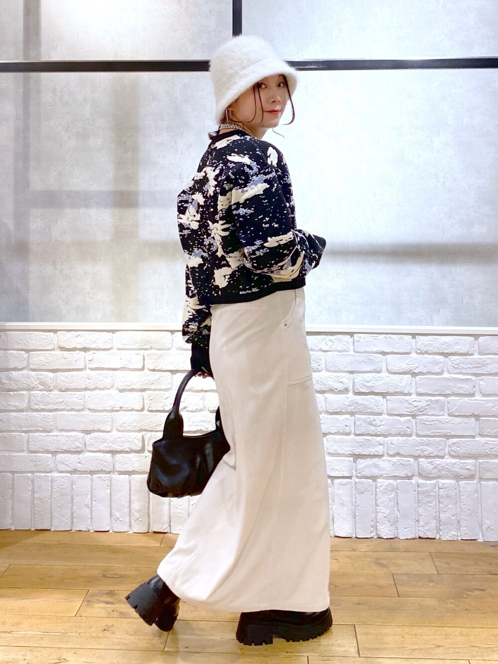 ブラック系のニット/セーター、ブラック系のハンドバッグ、ブラック系のブーツを着用したレディースの冬コーディネートの7枚目の写真