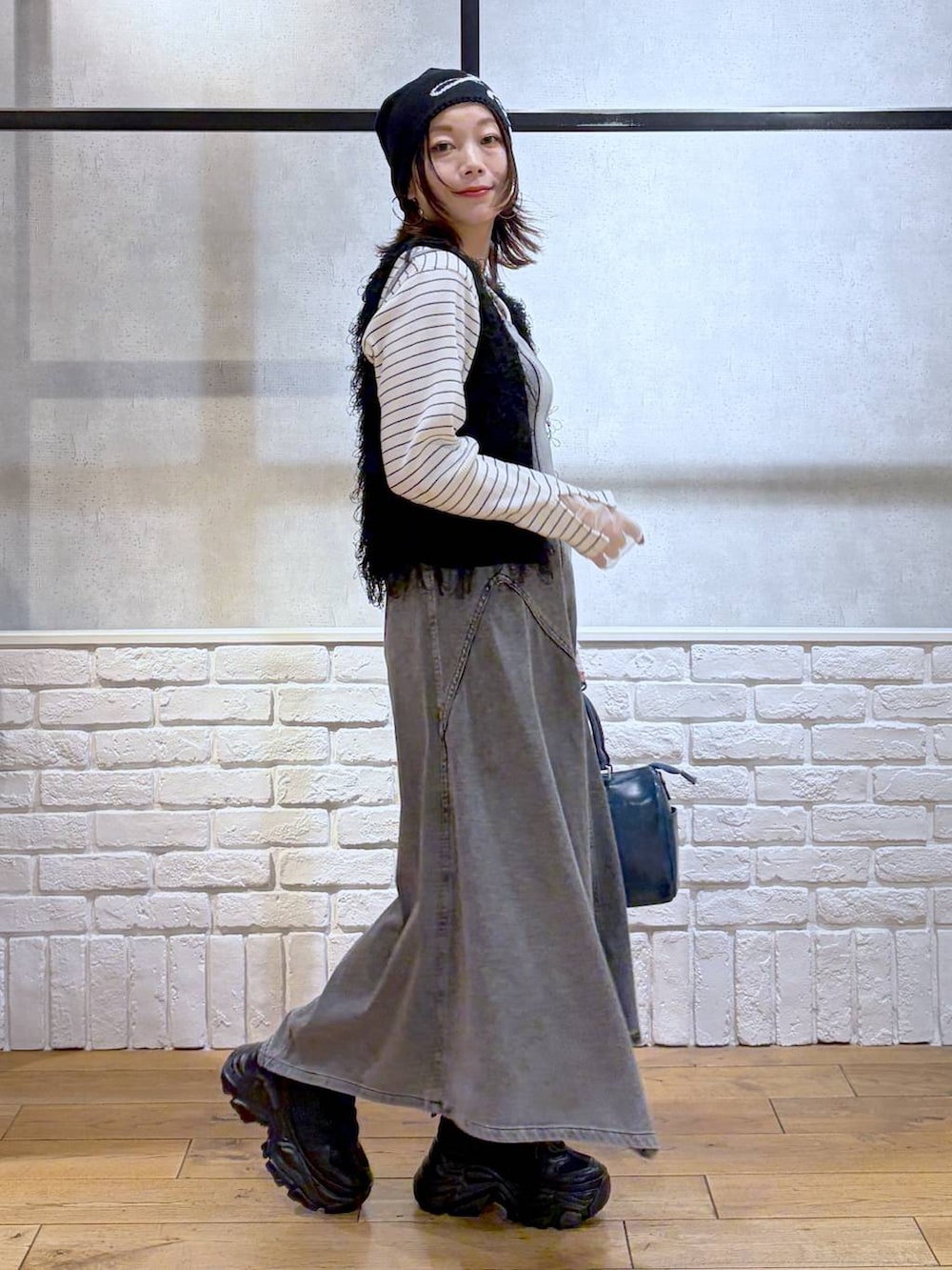 ブラック系のスニーカー、ブラック系のワンピース、ブルー系のショルダーバッグを着用したレディースの冬コーディネートの7枚目の写真