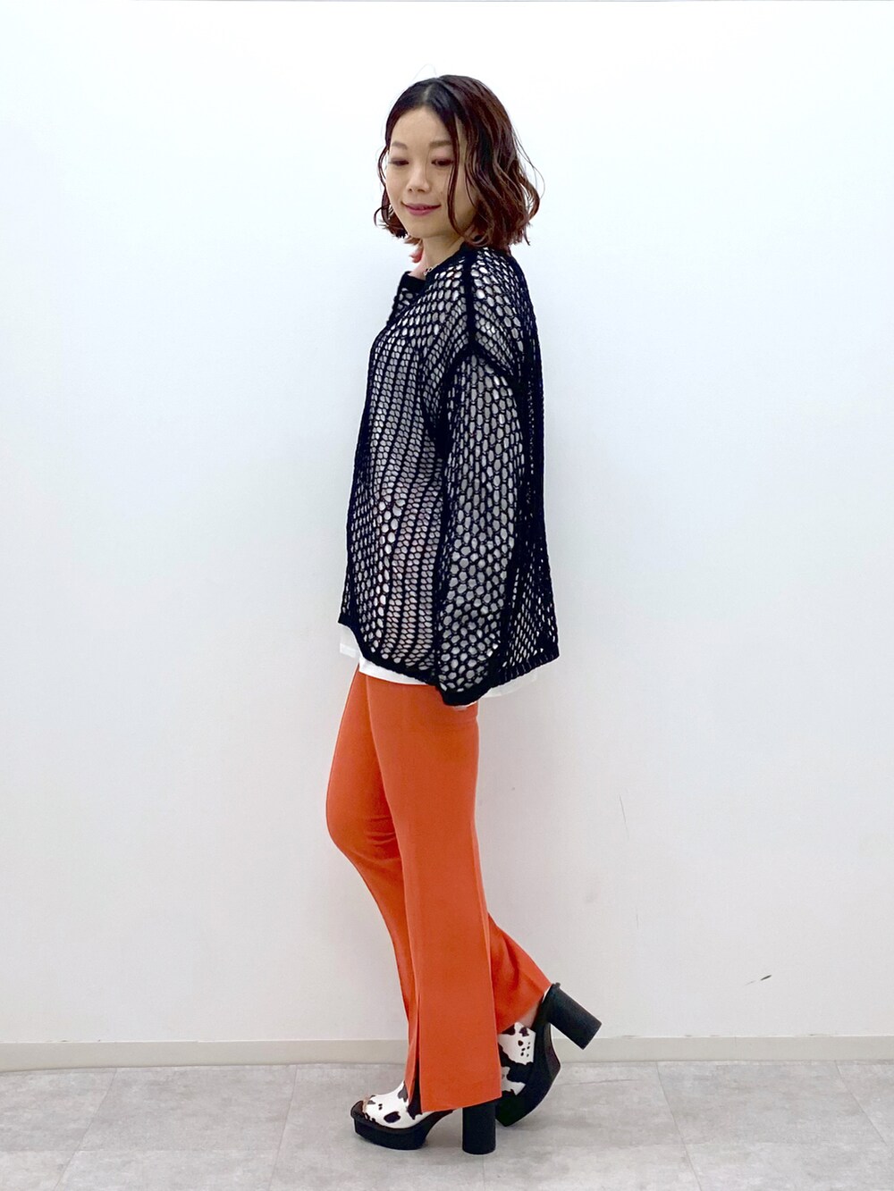 オレンジ系のその他パンツ、ホワイト系のサンダル、ブラック系のニット/セーターを着用したレディースの春コーディネートの4枚目の写真