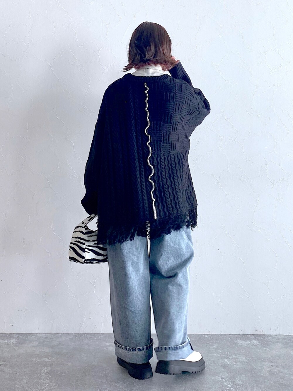 ブラック系のニット/セーター、ブルー系のデニムパンツ、ホワイト系のブーツを着用したレディースの夏コーディネートの4枚目の写真