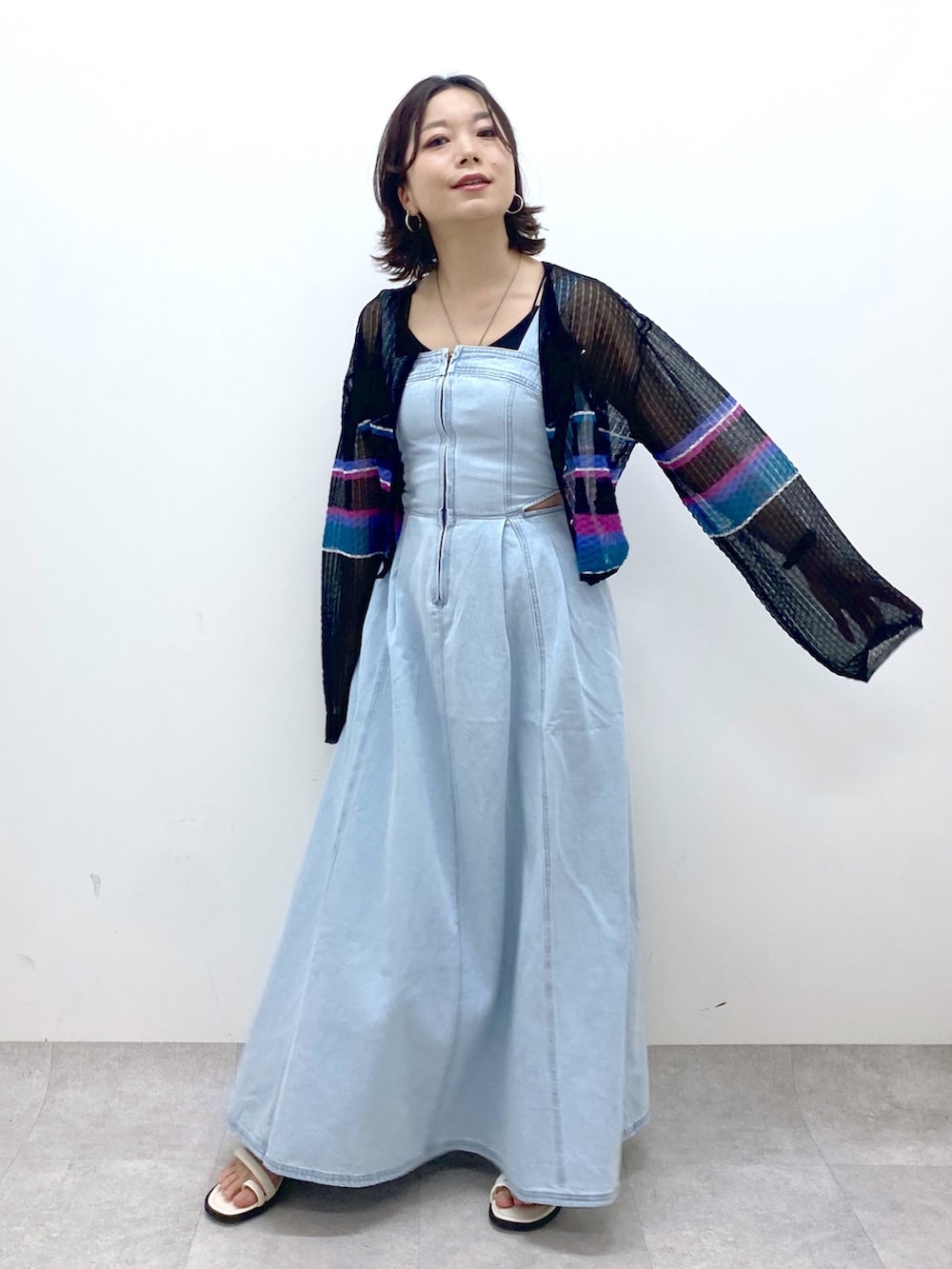 ブルー系のジャンパースカート、ホワイト系のサンダル、ブラック系のカーディガン/ボレロを着用したレディースの春コーディネートの5枚目の写真