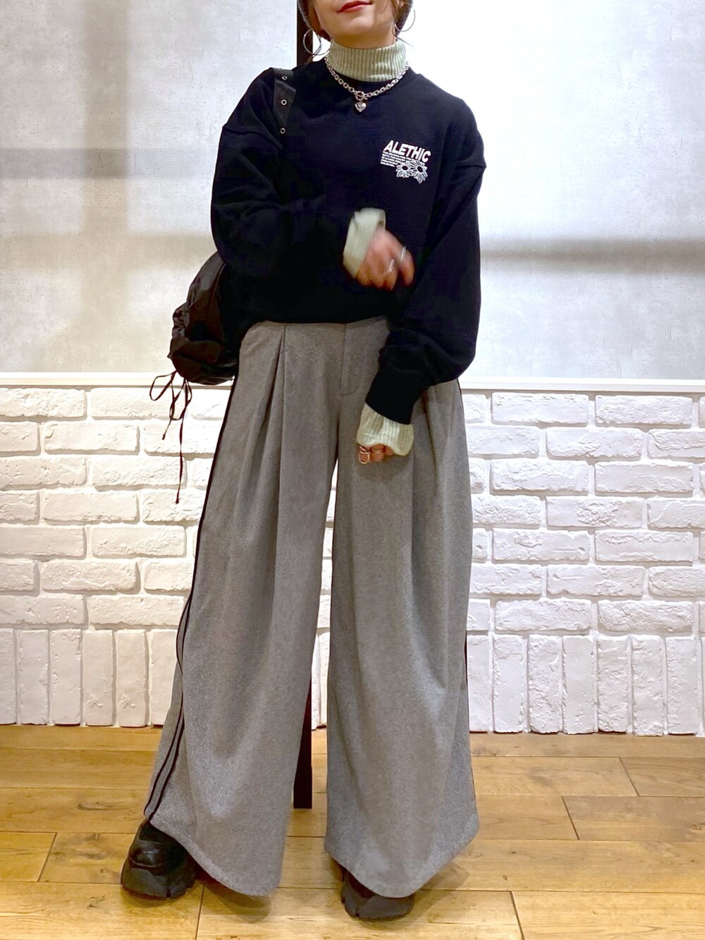 ブラック系のスウェット、グリーン系のショルダーバッグ、ブラック系のスラックスを着用したレディースの秋コーディネートの3枚目の写真