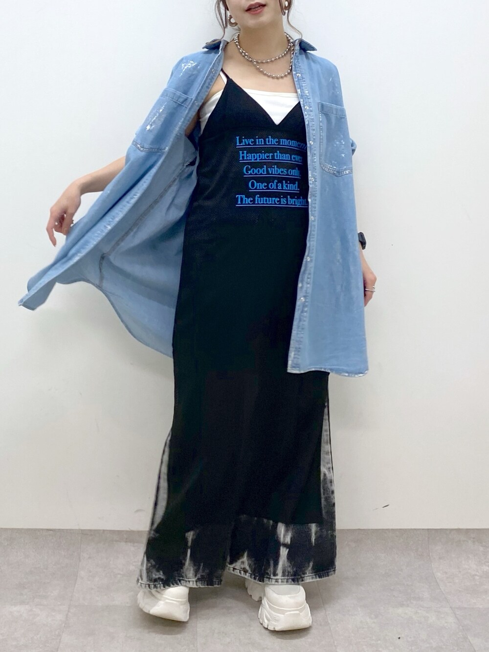 ブラック系のデニムパンツ、ホワイト系のスニーカー、ブラック系のワンピースを着用したレディースの春コーディネートの3枚目の写真